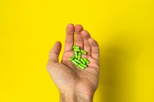 A person holding green capsules as a representation of Acacia standardized preparation